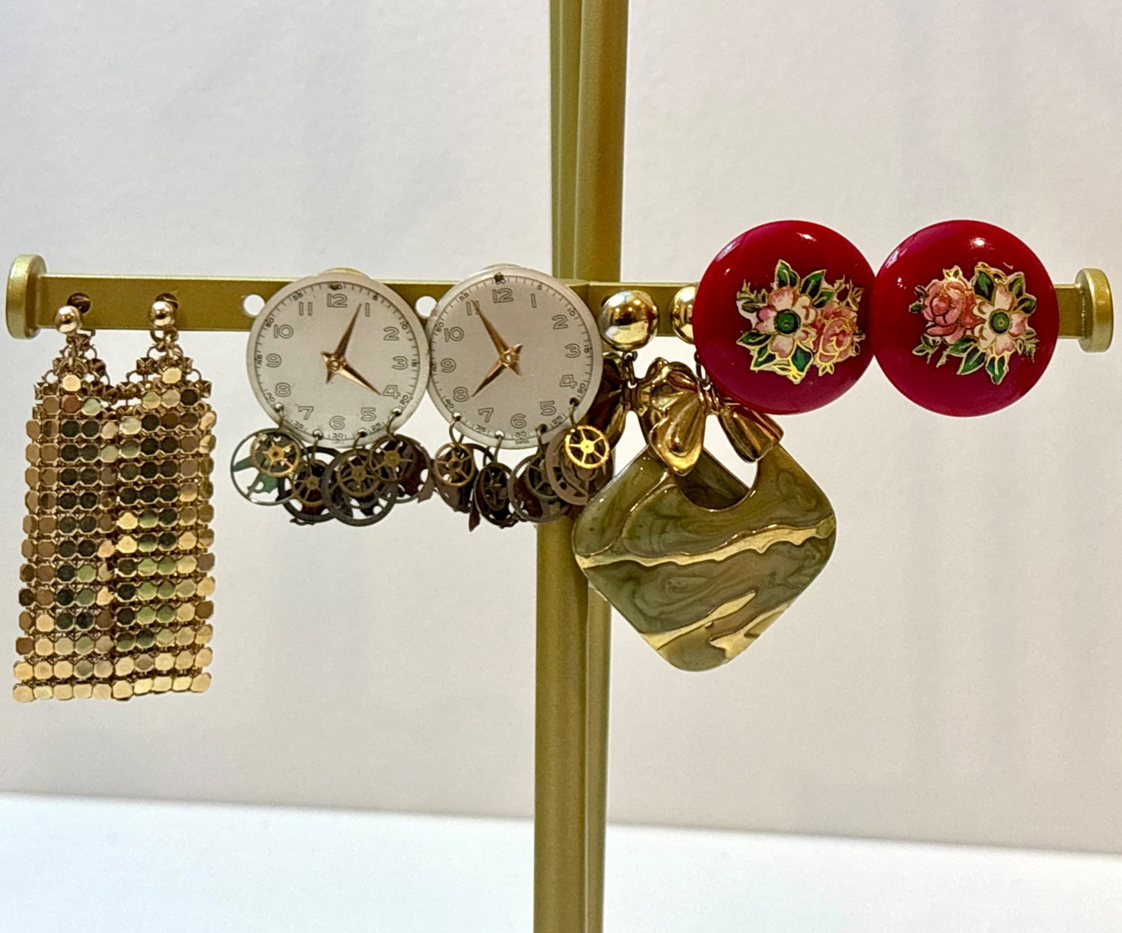 Assorted Vintage Earrings: Four pairs of earrings. Includes gold-tone mesh chain earrings, clock dial earrings with mechanical gear accents, circular red earrings adorned with floral designs, and green marbled earrings with