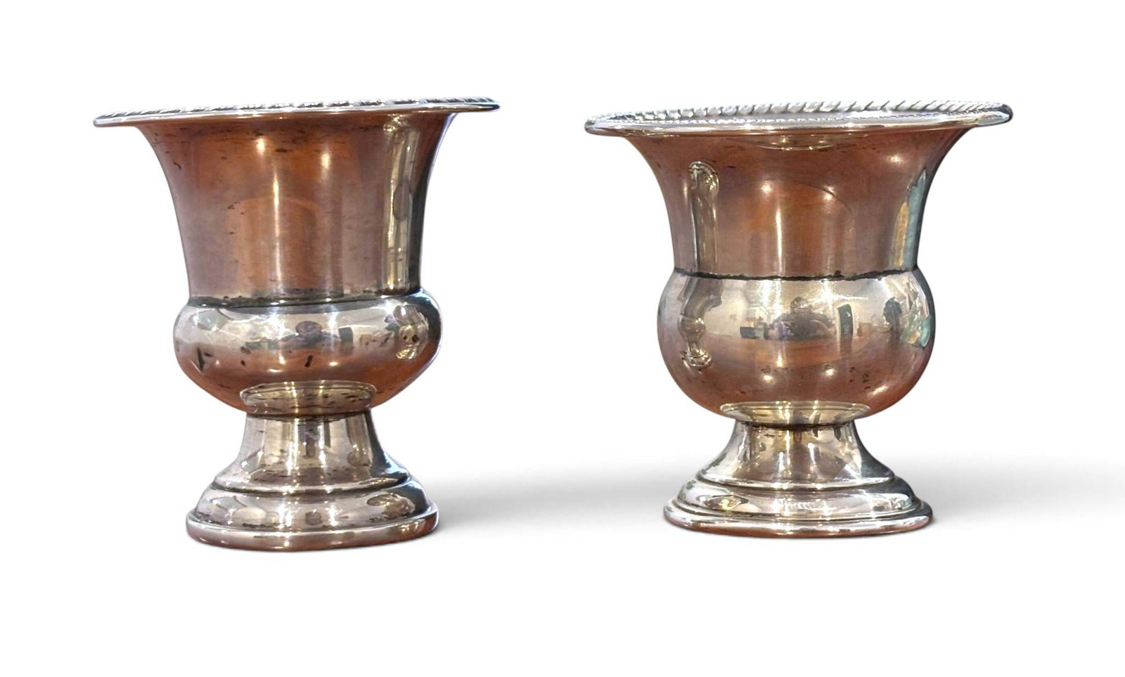 Empire Sterling Silver Urn Vases: Two matching sterling silver urn-shaped vases by Empire, marked on the base with ‘Empire Sterling’ and a model number (57). The vases feature a flared rim with a rope-like decorative edge and a ro