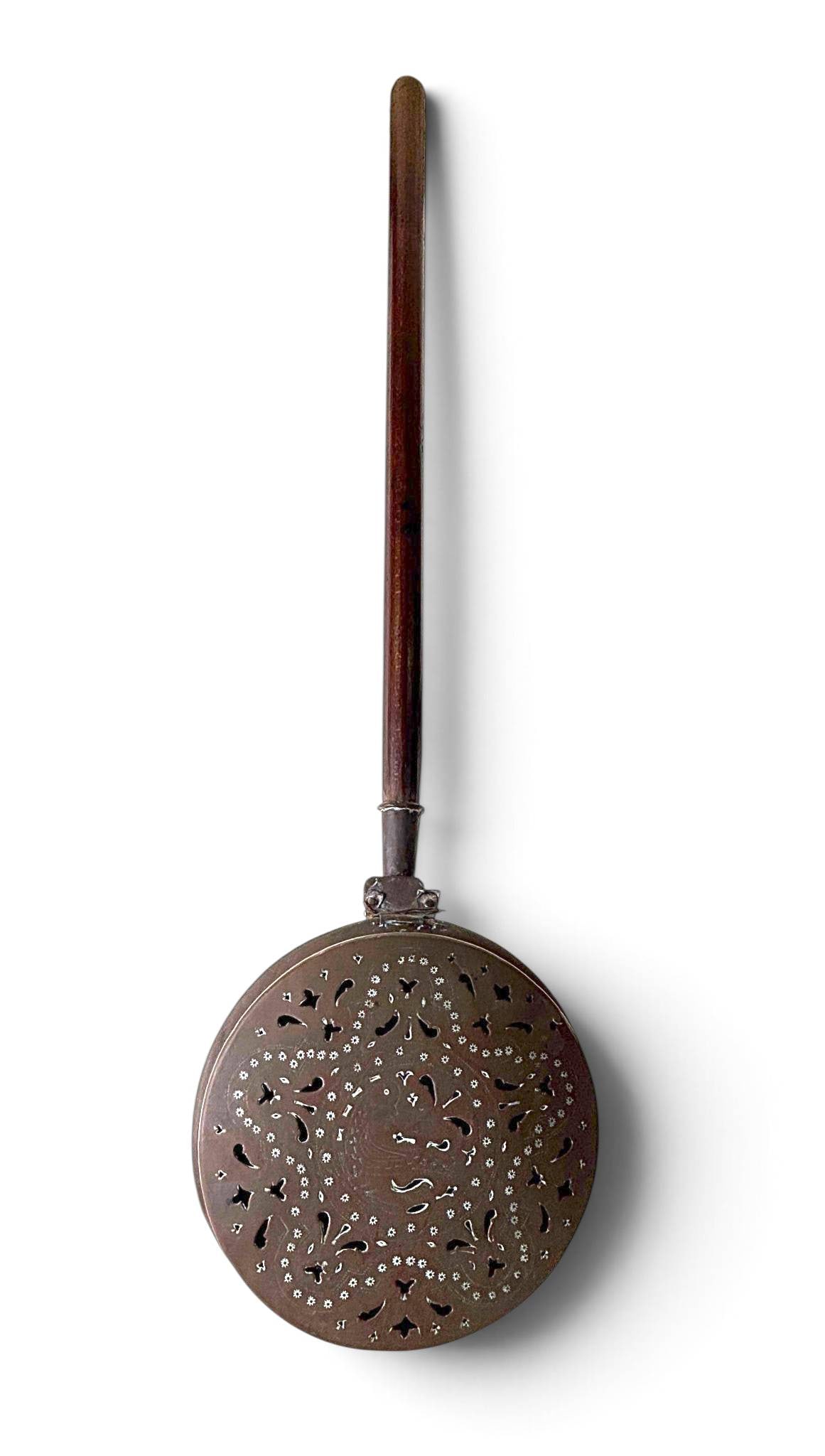 Antique Copper Bed Warmer with Perforated Lid: Antique copper bed warmer featuring a perforated lid with ornate patterns and a wooden handle. The back side of the lid is plain copper. The handle is broken and shows wear consistent with age and use
