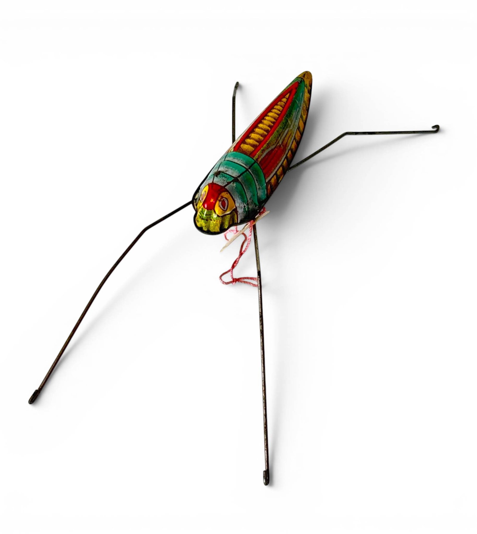 Tinplate Mechanized Grasshopper Toy: A vintage tinplate grasshopper toy with colorful hand-painted details on the body, featuring green, red, and yellow patterns. Metal wire legs extend from the body. The body underside shows signs of