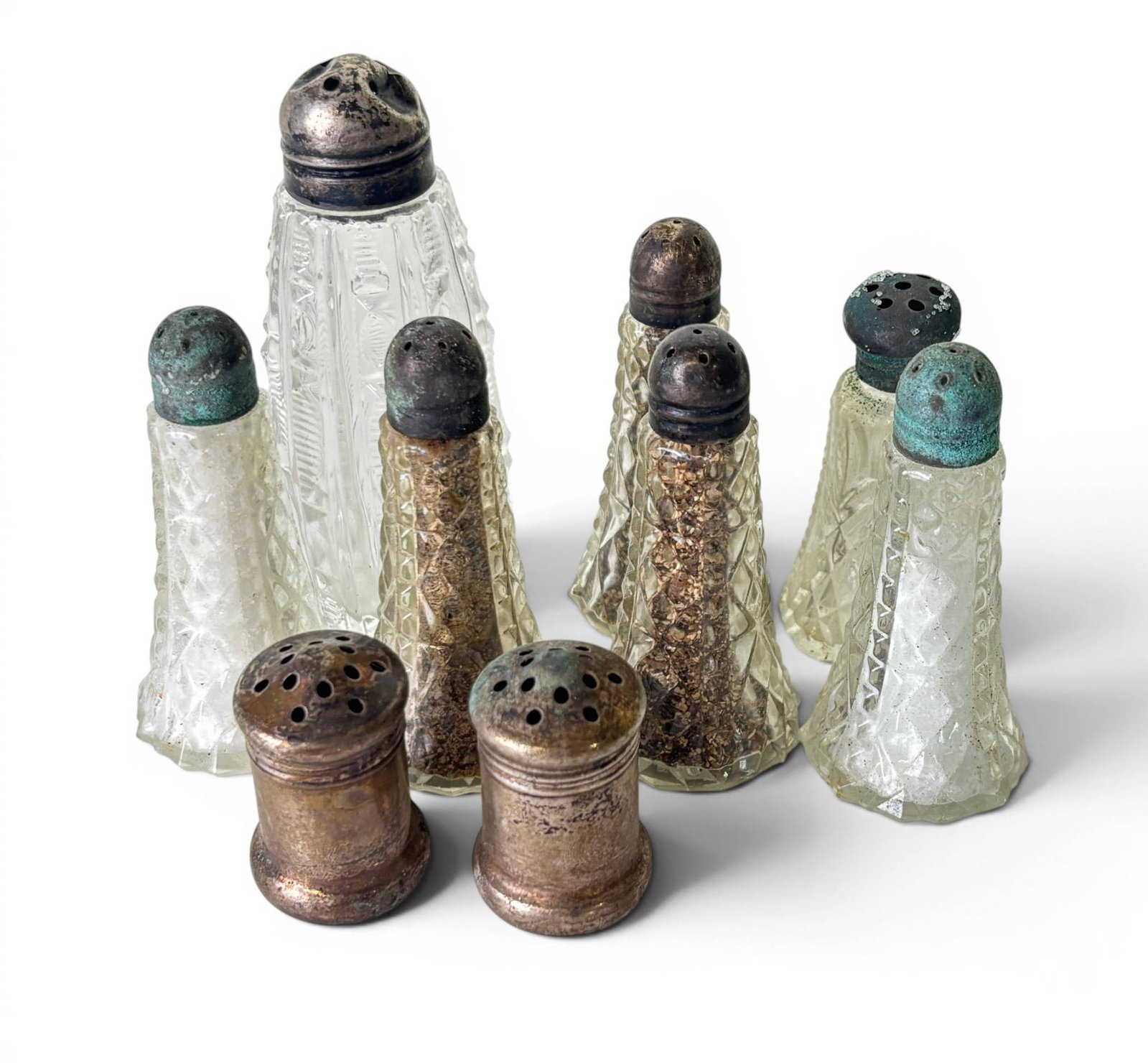 Sterling Silver and Pressed Glass Salt and Pepper Shakers: Eight salt and pepper shakers, comprising sterling silver tops and pressed glass bodies in varying designs and patterns. The sterling silver tops exhibit patina and tarnish consistent with age. Glass
