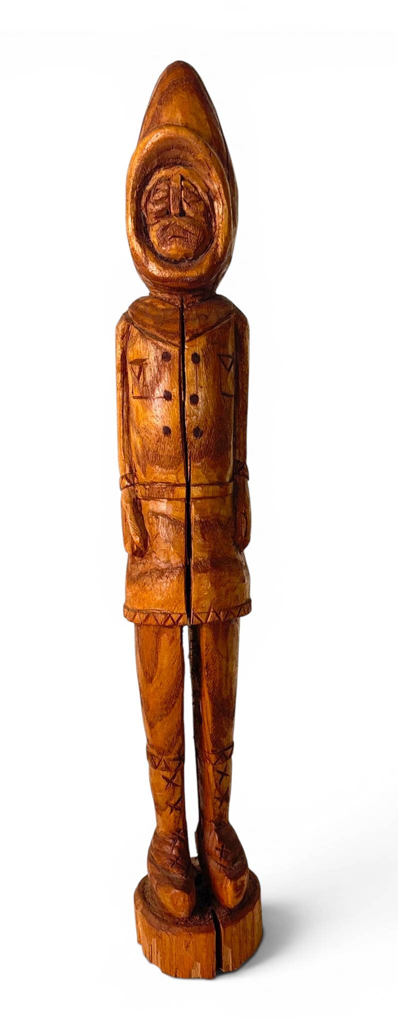 Hand-Carved Red Cedar Folk Art Figure: Folk art carving depicting a figure in hooded attire, crafted from red cedar wood. Features incised details on the clothing, including geometric patterns. The figure stands atop a circular base,