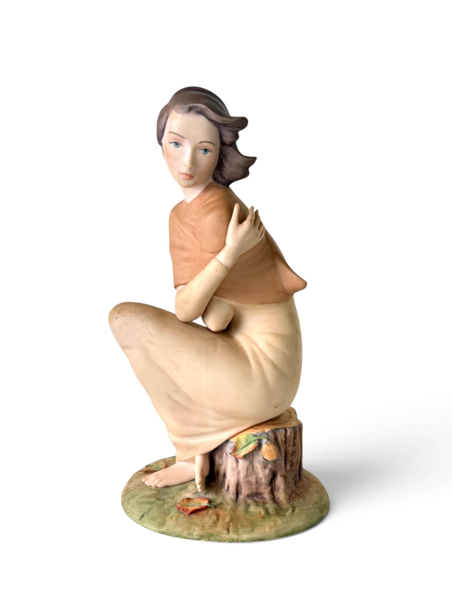 Laszlo Ispanky Porcelain Figurine Autumn Wind: Porcelain figurine designed by Laszlo Ispanky, depicting a woman seated on a tree stump with detailed hand-painted features. The base is marked with ‘Laszlo Ispanky,’ ‘Made in USA,’ and