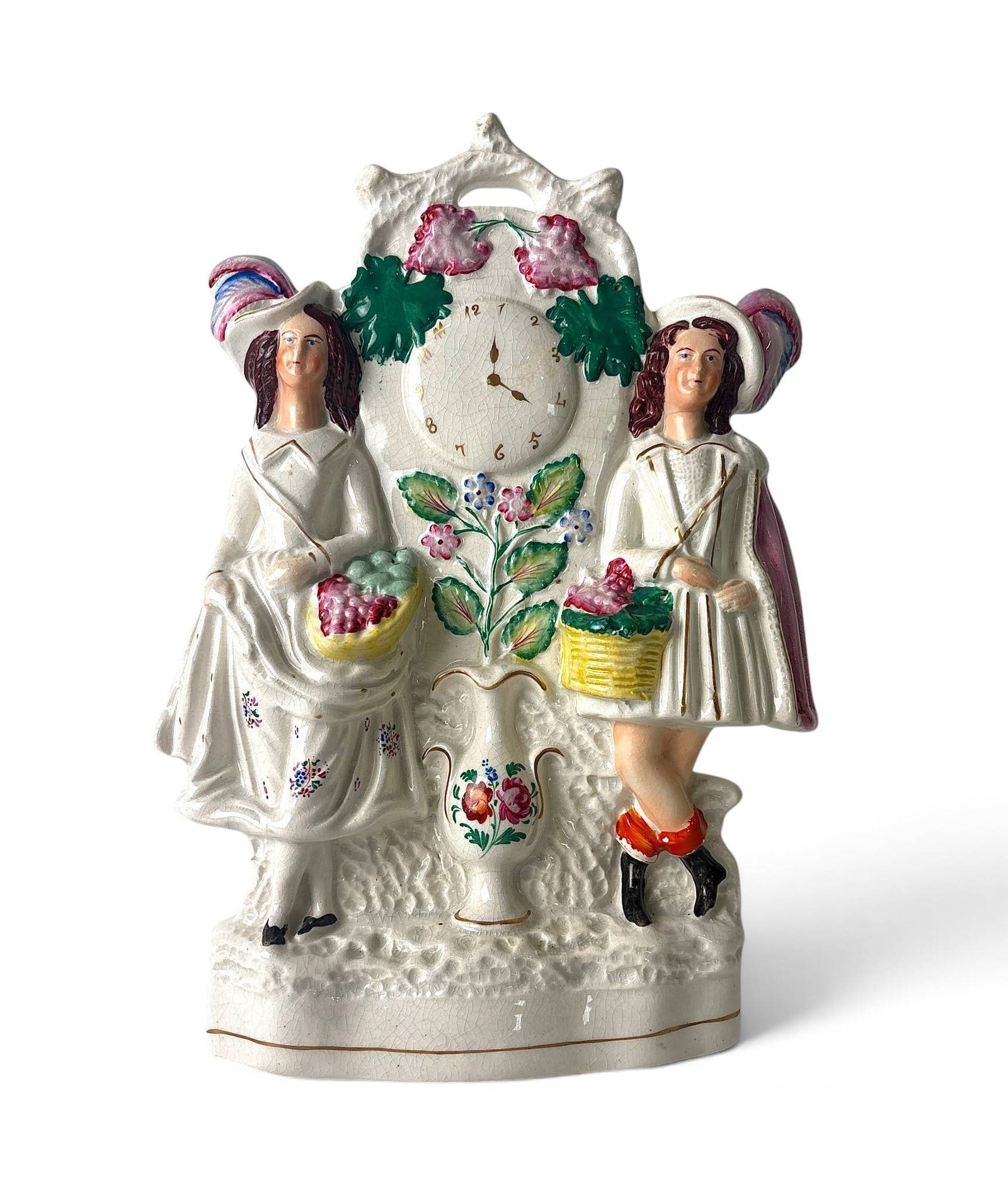 Staffordshire Figural Clock 19th Century: Staffordshire ceramic figural clock featuring two women in period attire, each holding a basket, flanking a central clock face adorned with painted floral garlands. Hand-painted floral and leaf