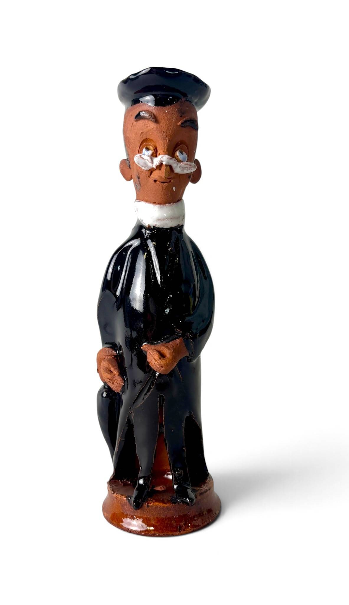 Chelsea Pottery Terracotta Figure: Terracotta figure crafted at Chelsea Pottery, representing a gentleman clad in black attire with a glossy glaze. The figure features detailed facial expressions with painted glasses and textured hands