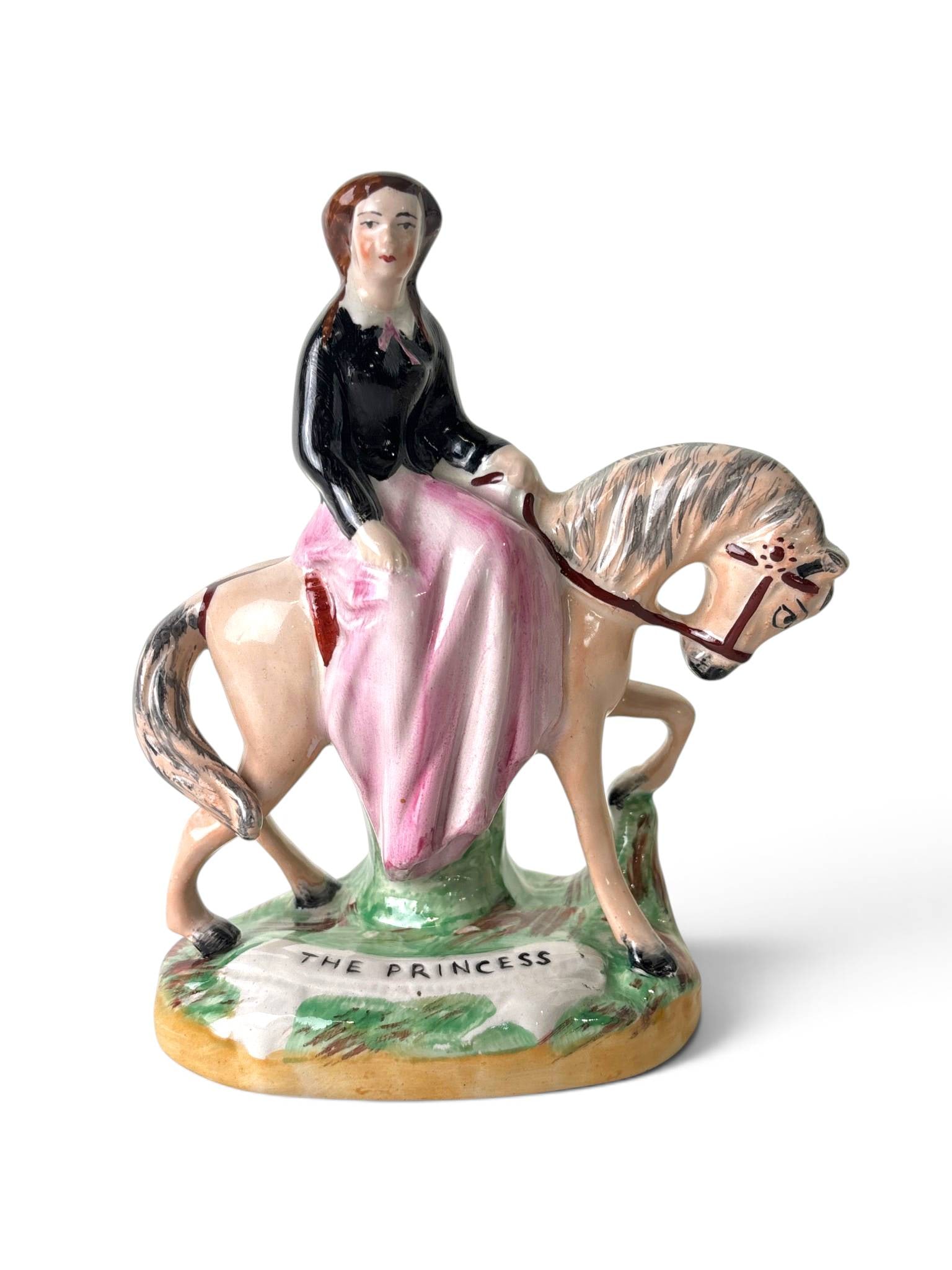 Staffordshire Ware ‘The Princess’ Figurine: Hand-painted earthenware figurine depicting a woman identified as ‘The Princess,’ riding sidesaddle on a horse. The base is inscribed with ‘The Princess,’ and the underside bears the black tra