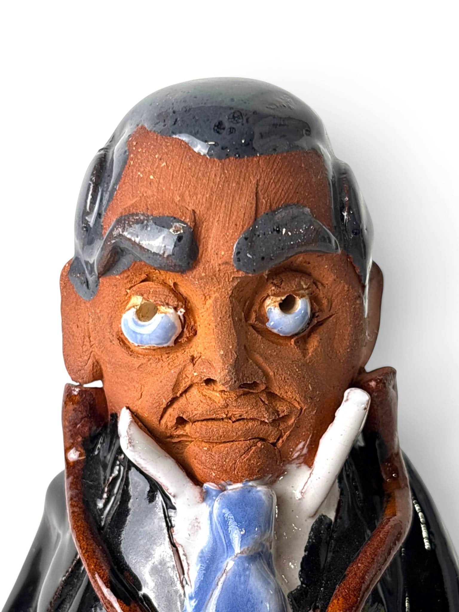 Chelsea Pottery Terracotta Figurine of a Man: Handcrafted terra cotta figurine depicting a man dressed in a black suit and blue tie, made by Chelsea Pottery. Features detailed facial expressions with hand-painted accents and a glossy glaze finish
