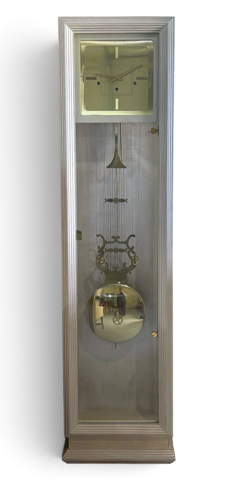 Sligh Trend Modern Grandfather Clock: Sligh grandfather clock featuring a sleek wooden case with a silver-toned finish and fluted design. The clock has a square brass-finished face with minimalist hour markers and slender hands. Inside, t