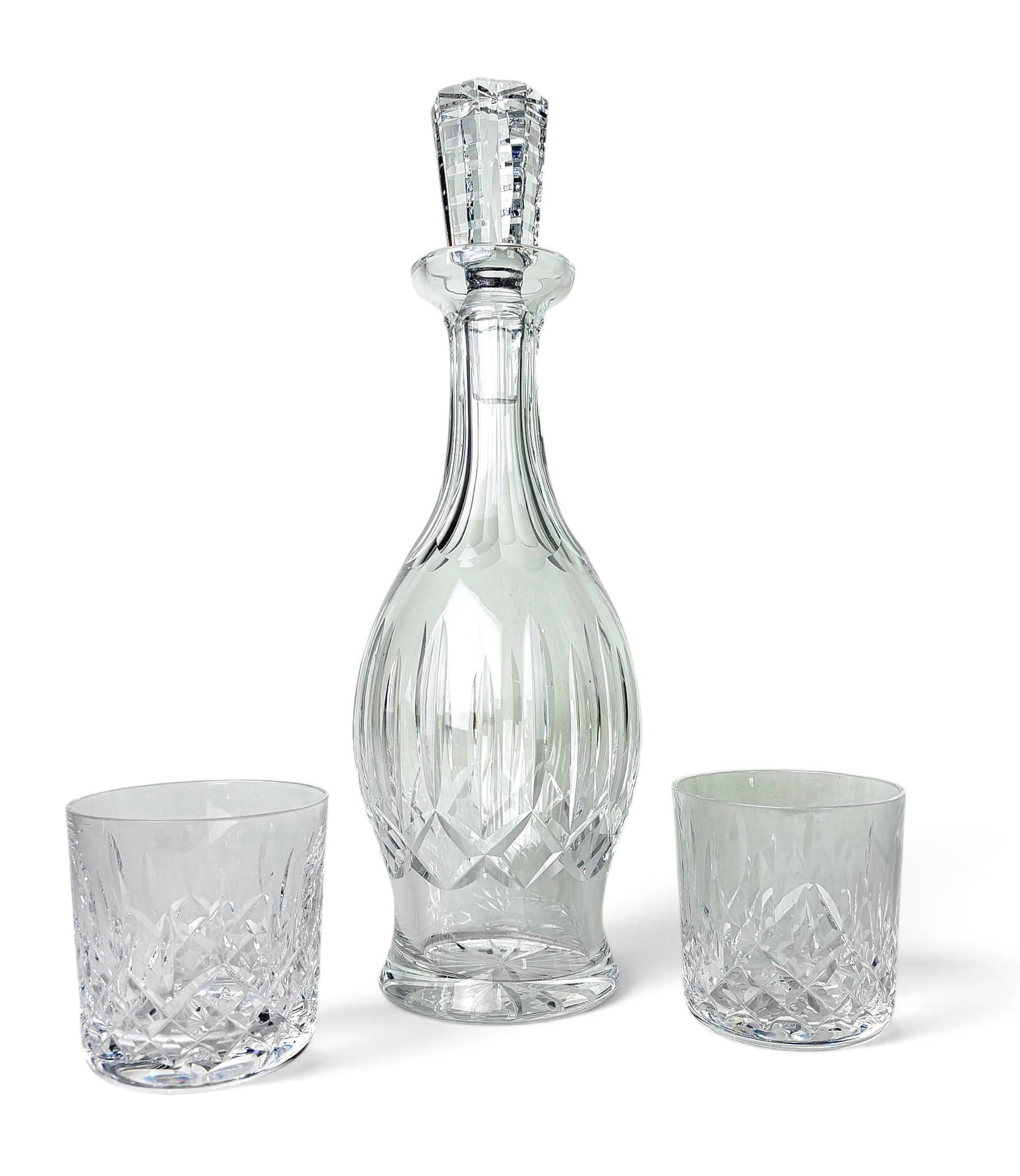 Waterford Lismore Decanter and Tumblers: Crystal decanter and two tumblers from the Waterford Lismore collection. The decanter features the iconic Lismore diamond and wedge-cut pattern with a faceted stopper. Each tumbler showcases the same