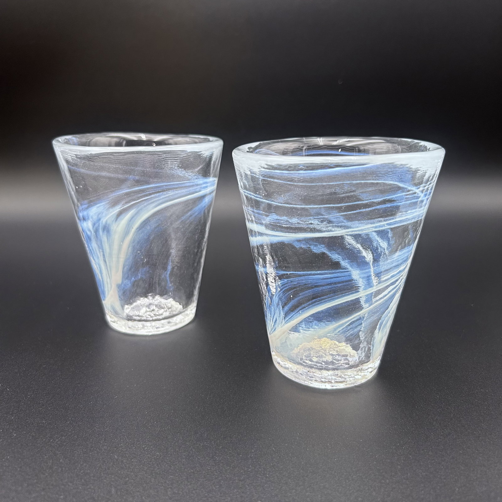 Two (2) Swedish Kosta Boda White Swirl Drinking Glasses Ulrica Hydman: Set of two (2) white vintage Kosta Boda swirl drinking glasses, designed by Ulrica Hydman Vallien, Sweden, 1980s. Each glass measures approximately 3.75 inches in diameter x approximately 4.25 inches 