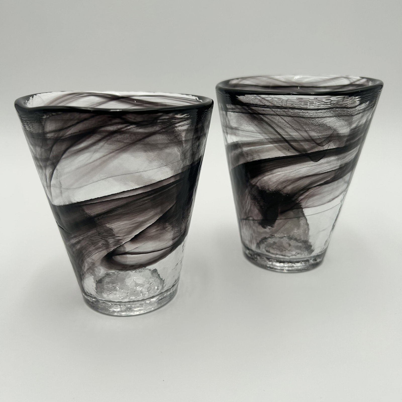 Two (2) Swedish Kosta Boda Black Swirl Drinking Glasses Ulrica Hydman: Set of two (2) black vintage Kosta Boda swirl drinking glasses, designed by Ulrica Hydman Vallien, Sweden, 1980s. Each glass measures approximately 3.75 inches in diameter x approximately 4.25 inches 