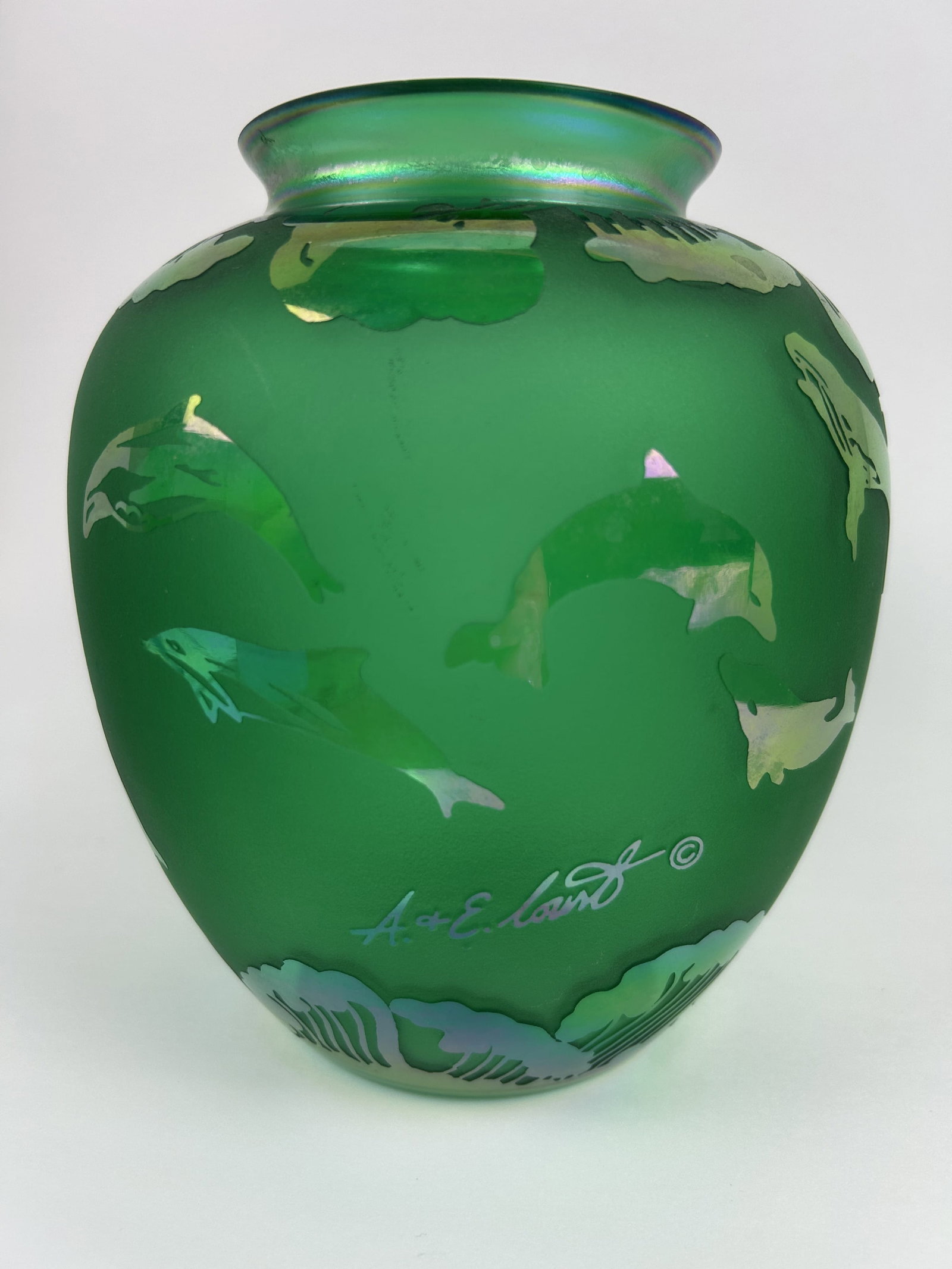 Arthur Court Iridescent Green Dolphins & Whales, Signed: The Arthur Court Iridescent Green Dolphins and Whales vase is a hand-signed piece of art glass that showcases a stunning design of marine animals. Made with hand-blown glass, this decorative item