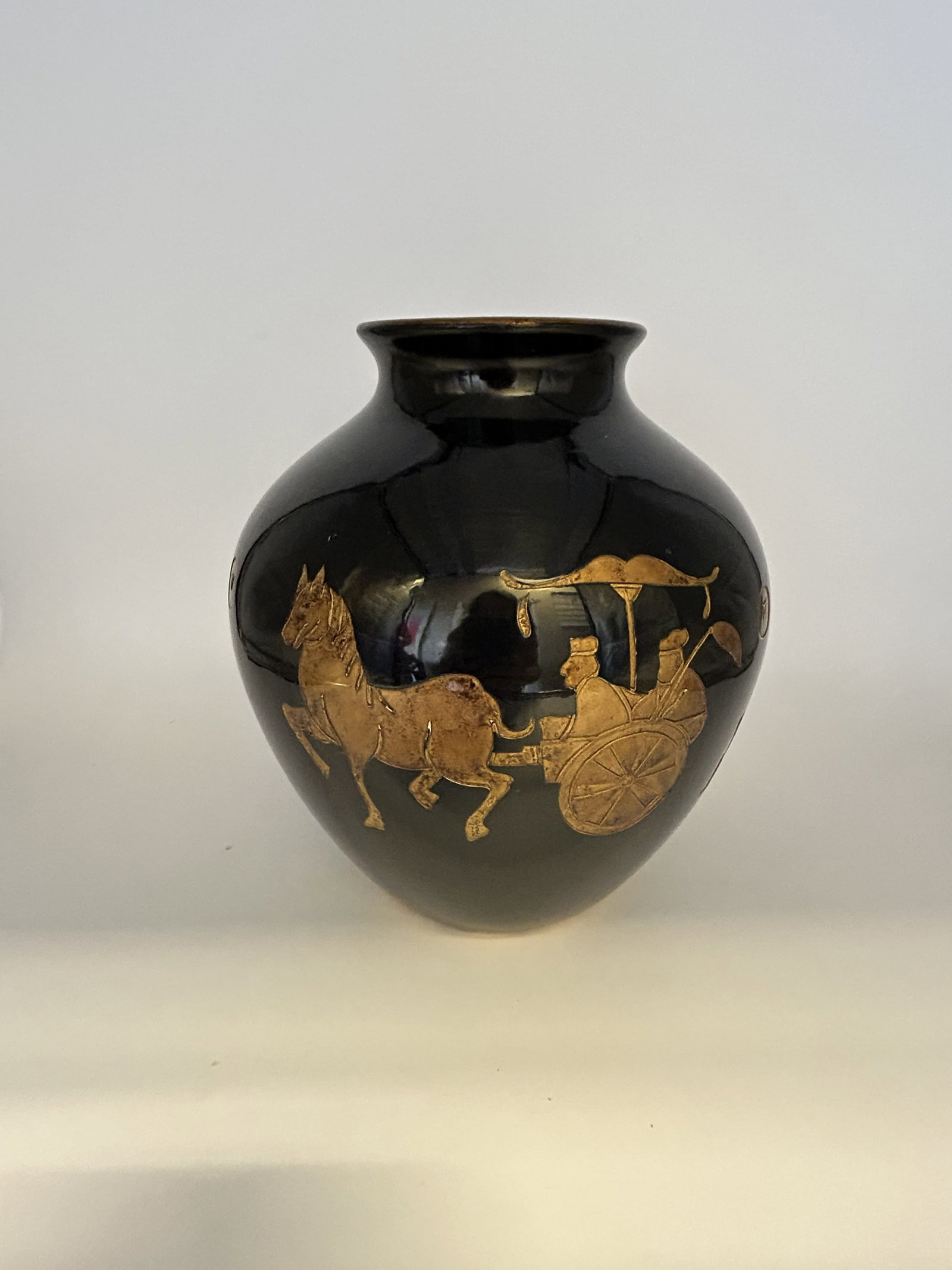 Black Ceramic Vase Gold Decoration depicting a Horse-Drawn Carriage Scene: Black ceramic vase with gold decoration depicting a horse-drawn carriage scene.
