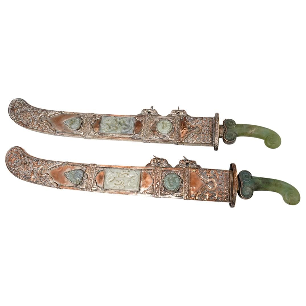Pair of Chinese Steel and Jade Ritual Swords in Copper Sheathes: Two matching ritual swords, each featuring a steel blade and curved jade handle and mounted in a copper sheath sporting etched and raised floral, foliage, and lotus designs and finished with six chilo