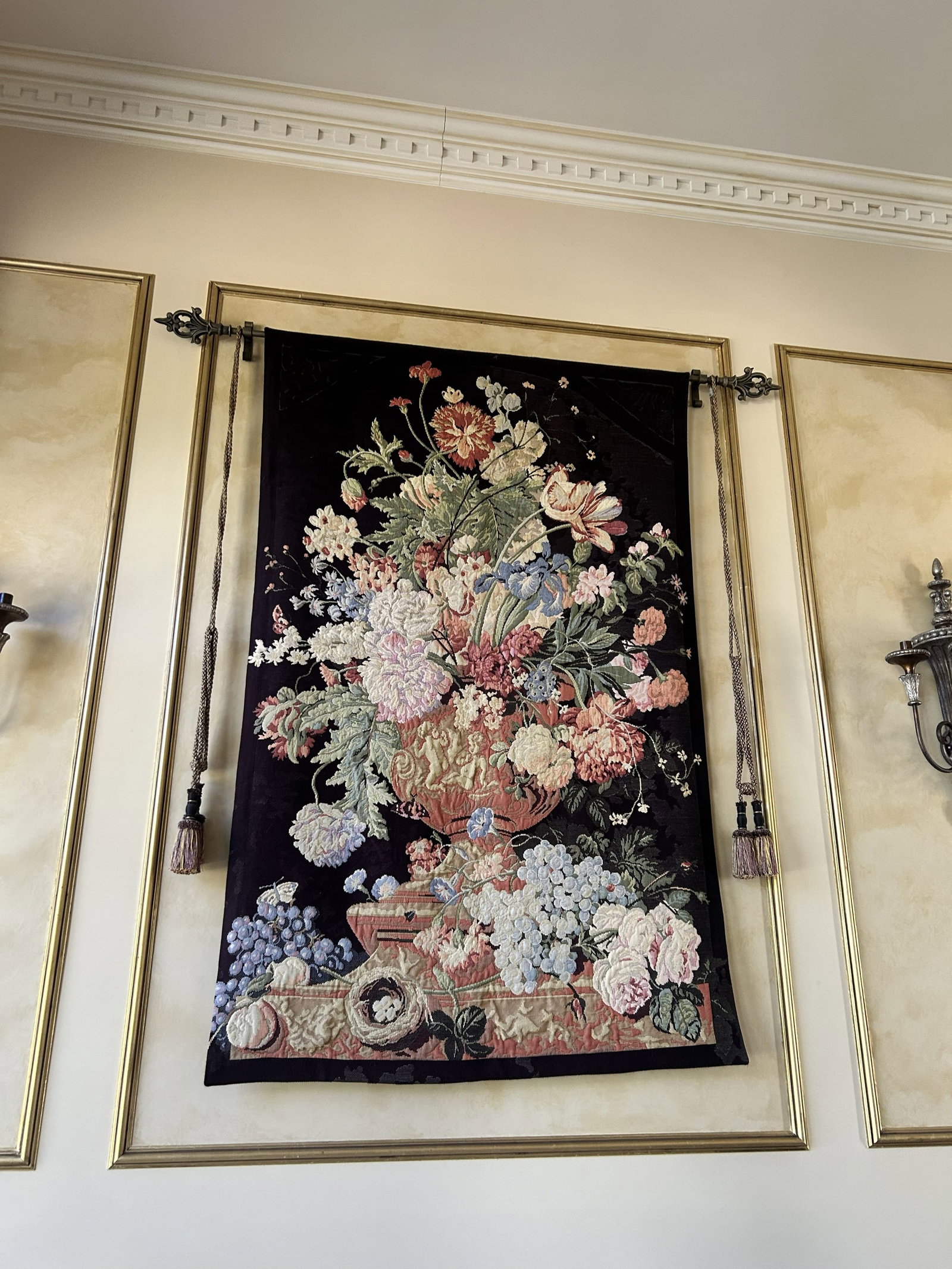 Large Vintage Hanging French-Style Tapestry Wall Art: This is a large vintage hanging French-style woven tapestry wall art featuring a colorful floral arrangement on a black background, often referred to as a "Flemish Still Life" design. It comes with th