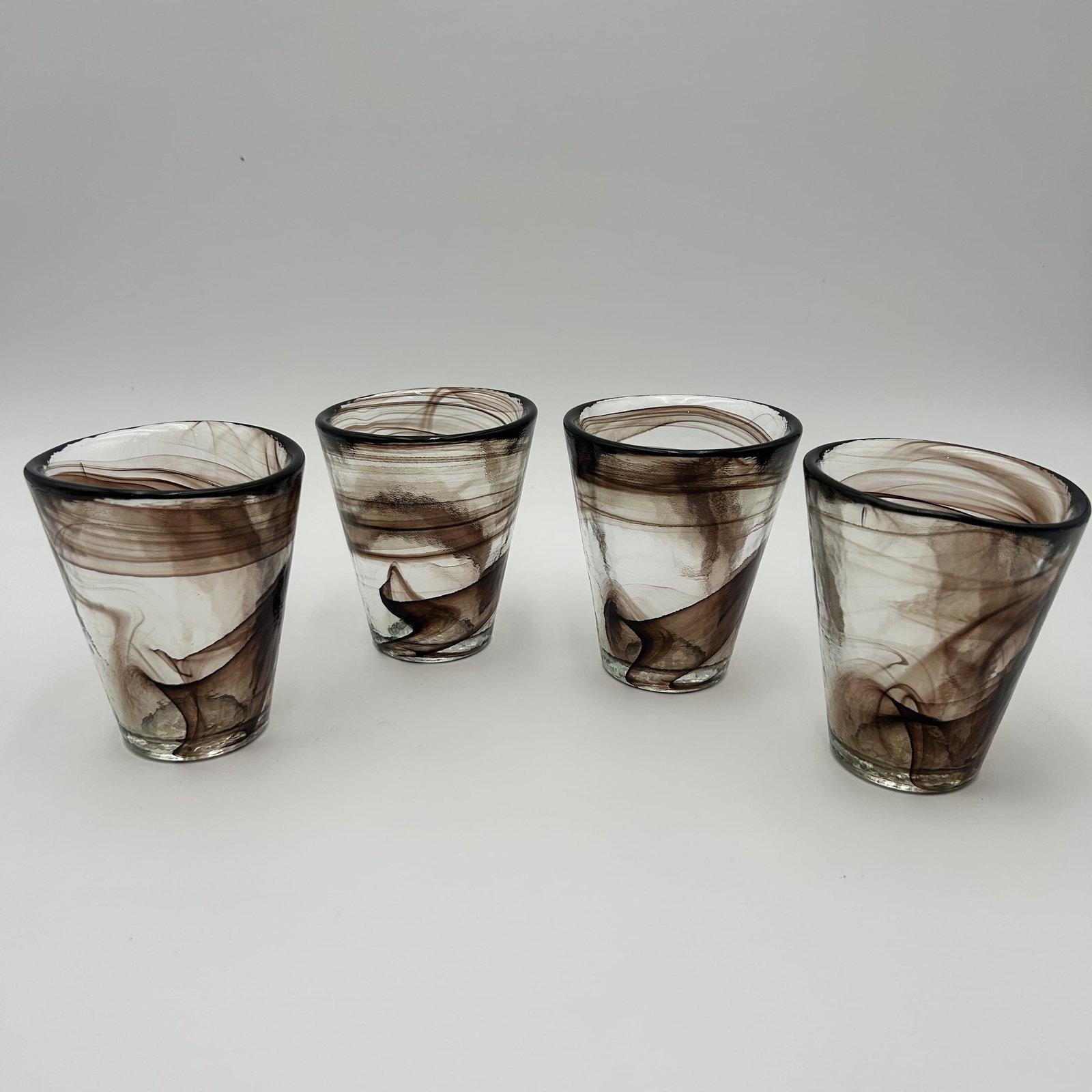 Four (4) Swedish Kosta Boda Brown Swirl Drinking Glasses Ulrica Hydman: Set of four (4) brown vintage Kosta Boda swirl drinking glasses, designed by Ulrica Hydman Vallien, Sweden, 1980s. Each glass measures approximately 3.75 inches in diameter x approximately 4.25 inches