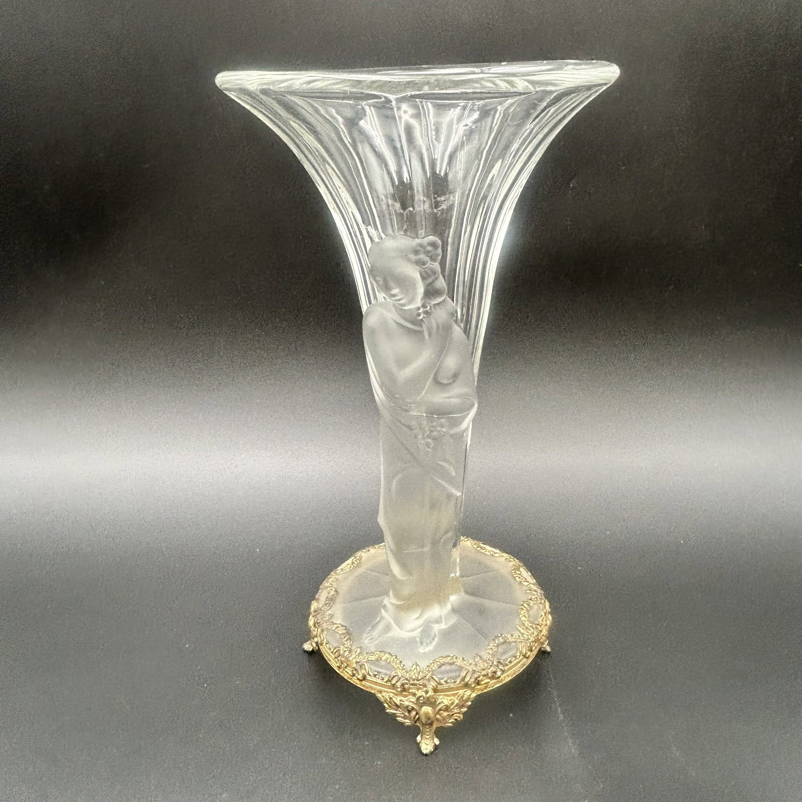 Vintage Pressed Glass Vase with frosted Glass Woman: This is a vintage clear pressed glass vase with satin frosted glass woman, set in ornate brass footing. The vase is fluted. The barefoot woman is with flowers in her hair and on her dress. Dimensions