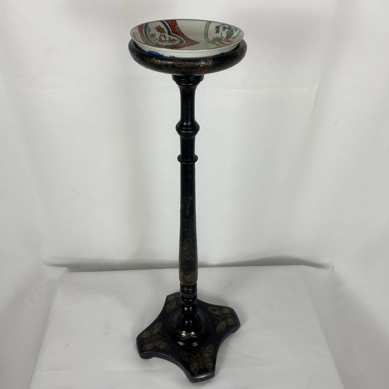 Antique Chinoiserie black lacquer Pedestal Table: This is an antique Chinoiserie black lacquer pedestal table or stand featuring delicate hand-painted motifs and flared quatrefoil base. Dimensions: 10" W x 28" H Dish: 6 1/4" Diameter