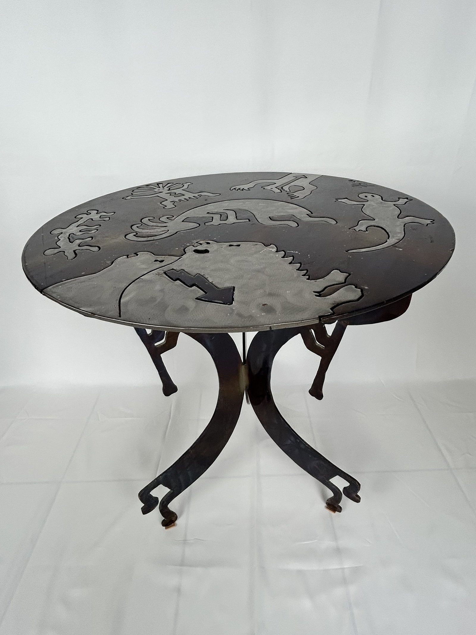 Hand-Crafted Metal Table Southwestern and Native American-inspired Tabletop: This is a hand-crafted metal table featuring prominent Southwestern and Native American-inspired iconography cut into the tabletop. The tabletop is crafted from heavy-gauge steel or iron. The finish