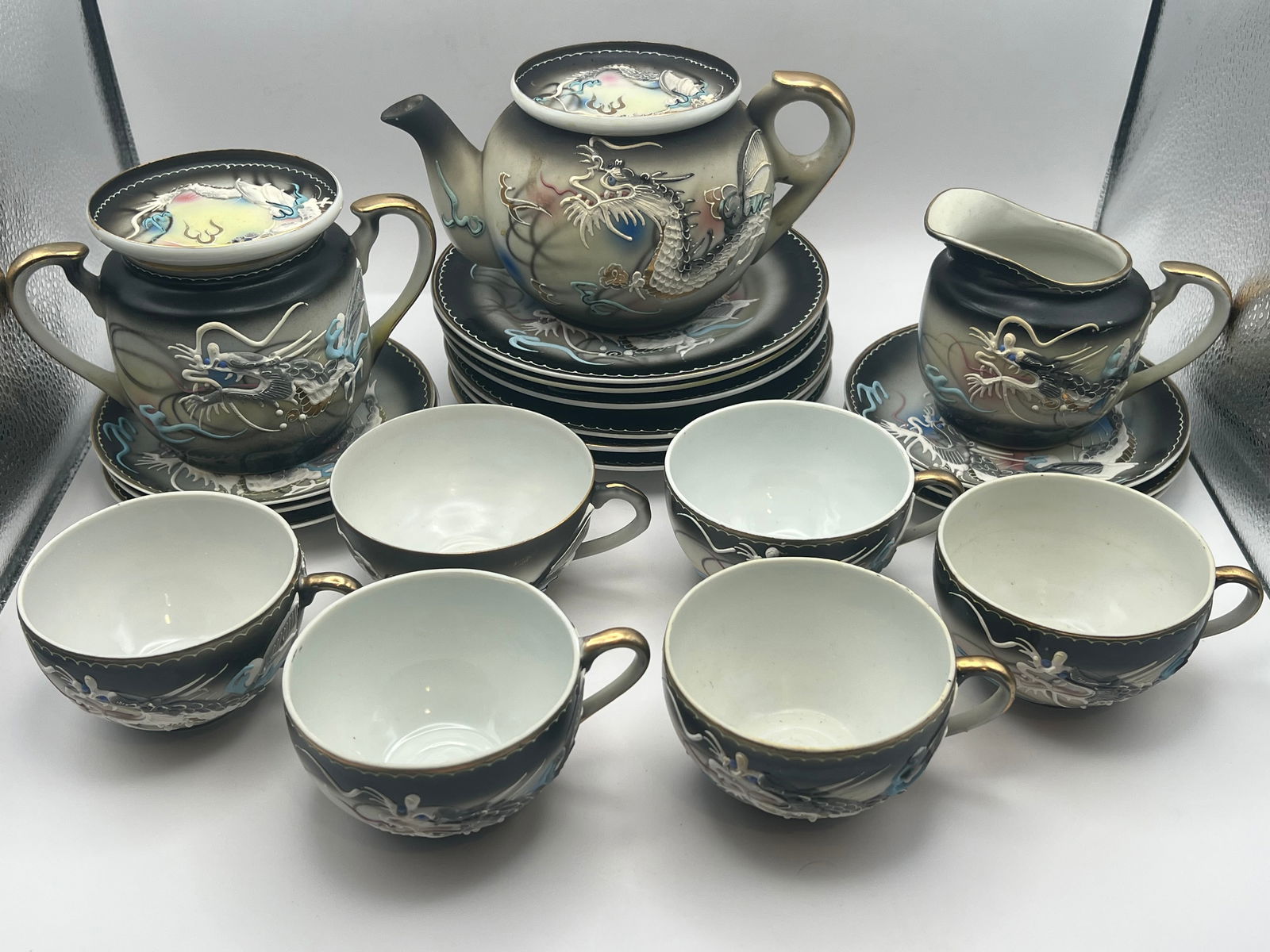 Geisha Girl "Dragonware" Moriage Tea Set: A set of Geisha Girl black "Dragonware" porcelain china with moriage & lithophane decoration. Includes 6 tea cups, 6 saucers, 6 dessert plates, 1 teapot, 1 creamer, & 1 sugar bowl.