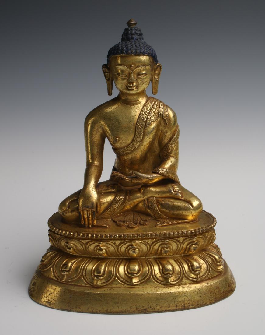 GILT BRONZE EARTH CALLING BUDDHA: Gilt Bronze Earth Calling Buddha: The Buddha's grape hair is patinaed blue, his earlobes are elongated. He is clad in simple robes and seated in the lotus position on a double lotus pedestal.