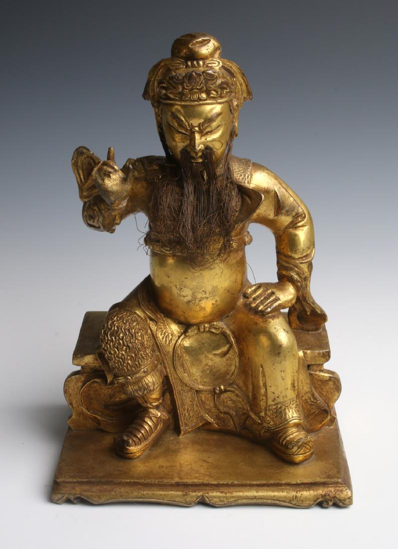 GILT BRONZE EMPEROR WITH APPLIED BEARD.: Gilt Bronze Emperor With Applied Beard. : An emperor is sitting on a simple throne with one hand resting on his knee, the other is gesturing at chest-height. His attached beard is formed from wire. <