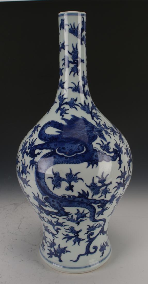 BLUE AND WHITE DRAGON VASE: Blue And White Dragon Vase: A blue and white vase in the style of a phoenix tail with two dragons (one faces up, the other down) among ruyi-shaped flowers. The neck is narrow and comes to sloped shou