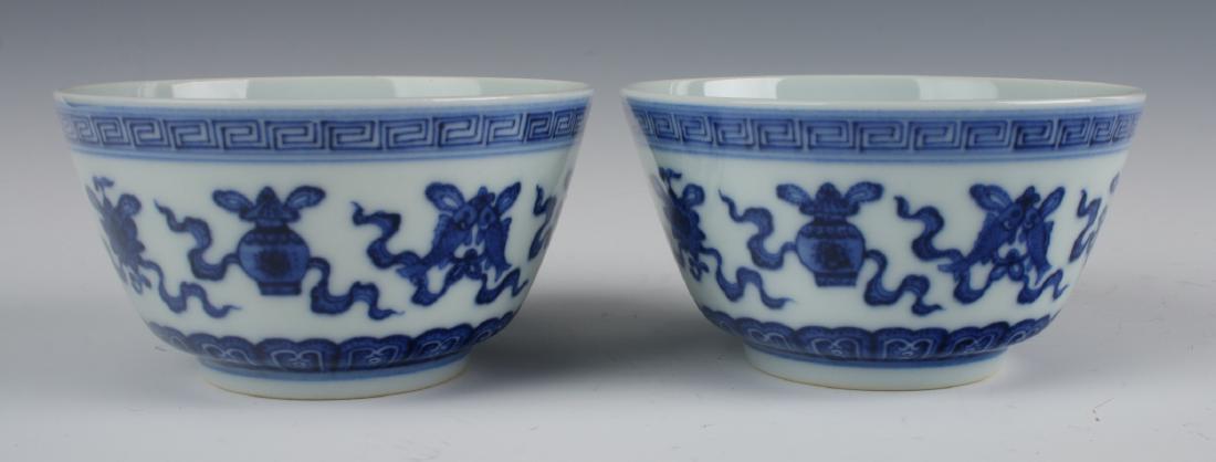 PAIR OF YONG ZHENG TEA CUPS: Pair Of Yong Zheng Tea Cups: The exterior is painted in scholar's items under a meander border and over a lotus petal border. The interior is white. Marked on the bottom.