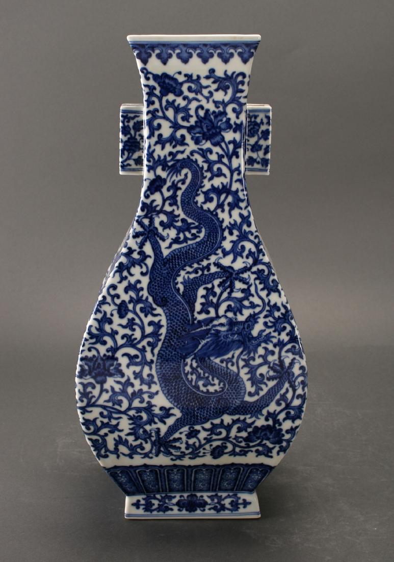 DRAGON AND PHOENIX VASE: Dragon And Phoenix Vase: Blue and white vase with squared, lobed handles decorated in flower and tendrils. A flower and tendril background covers the vase. The front and back are decorated with a dra