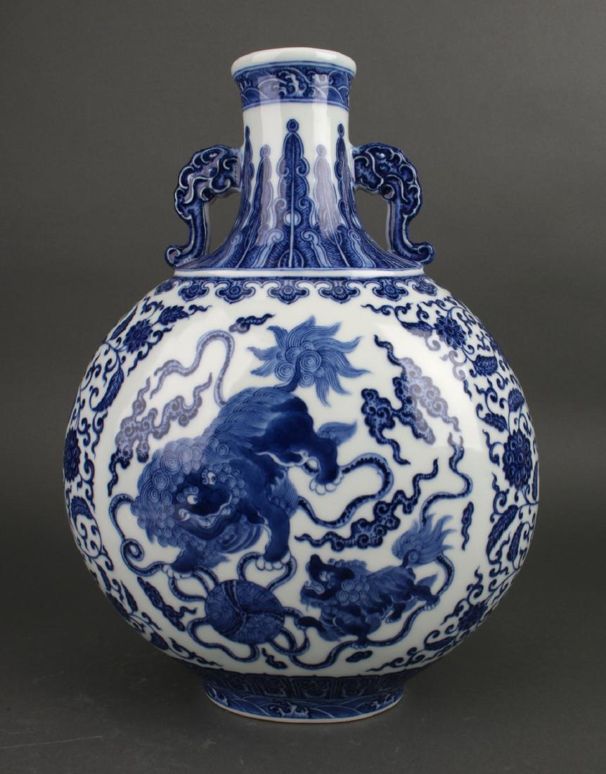 BLUE AND WHITE MOON FLASK: Blue And White Moon Flask: A blue and white Foo dog moon flask with a central reserve of an adult and pup foo dogs playing with a large ball amid ribbons and clouds. The sides are flower and tendril