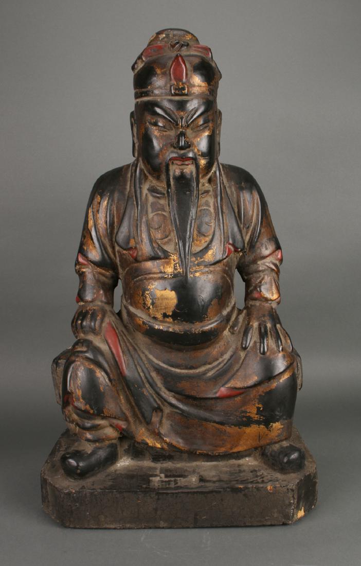 WOODEN SEATED EMPEROR STATUE: Wooden Seated Emperor Statue: An emperor is seated, draped in robes, on a low throne. This carving retains much of its black, red, and gold paint. There are some losses of paint, particularly on the