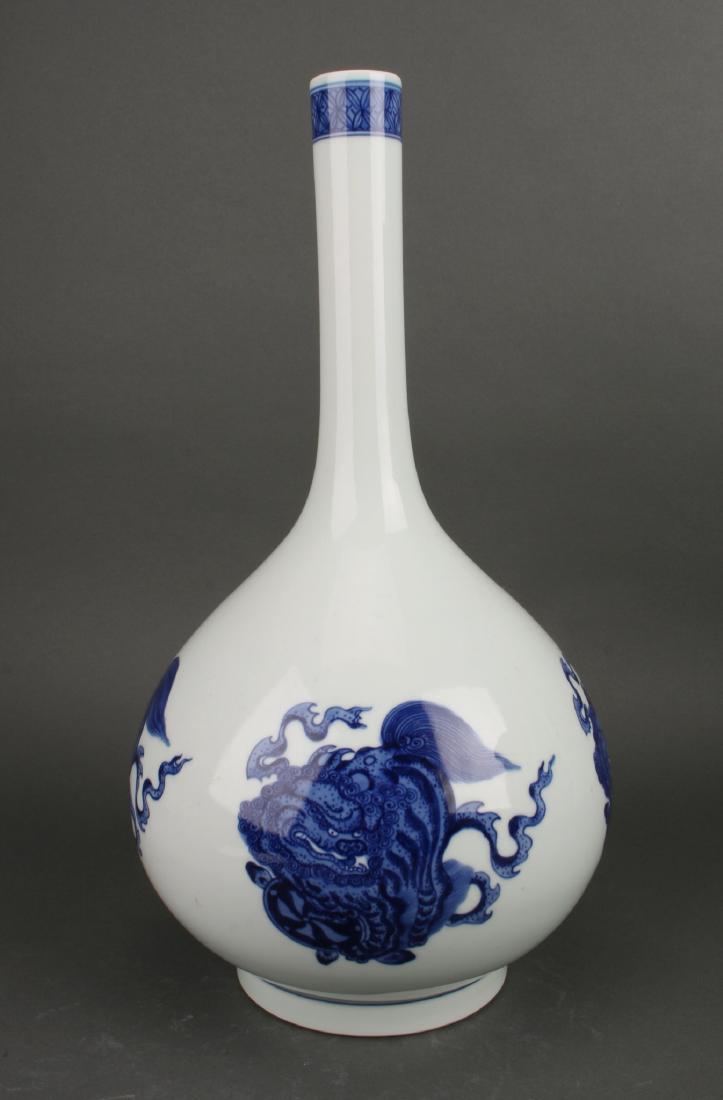 BLUE AND WHITE BOTTLE VASE: Blue And White Bottle Vase: A blue and white bottle vase with four reserves of foo dogs playing with balls. Blue flower border at the top of the neck. Marked on the bottom.
