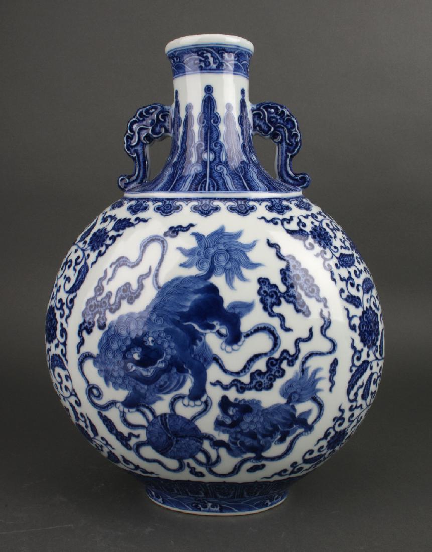 BLUE AND WHITE MOON FLASK: Blue And White Moon Flask: A blue and white foo dog moon flask with a central reserve of an adult and pup foo dogs playing with a large ball amid ribbons and clouds. The sides are flower and tendril p