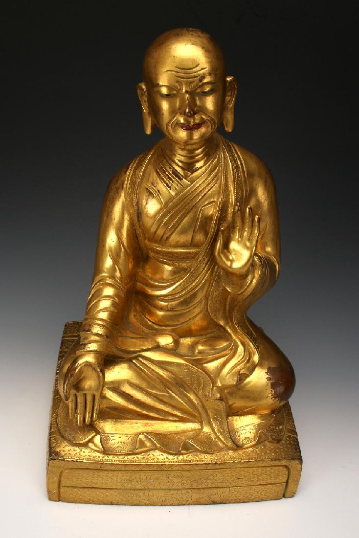 BRONZE BUDDHA: Bronze Buddha: A bronze teaching Buddha in flowing robes, seating in the lotus position on top of a raised cushion. His earlobes are elongated, and has a contemplative expression. Marked on the bottom