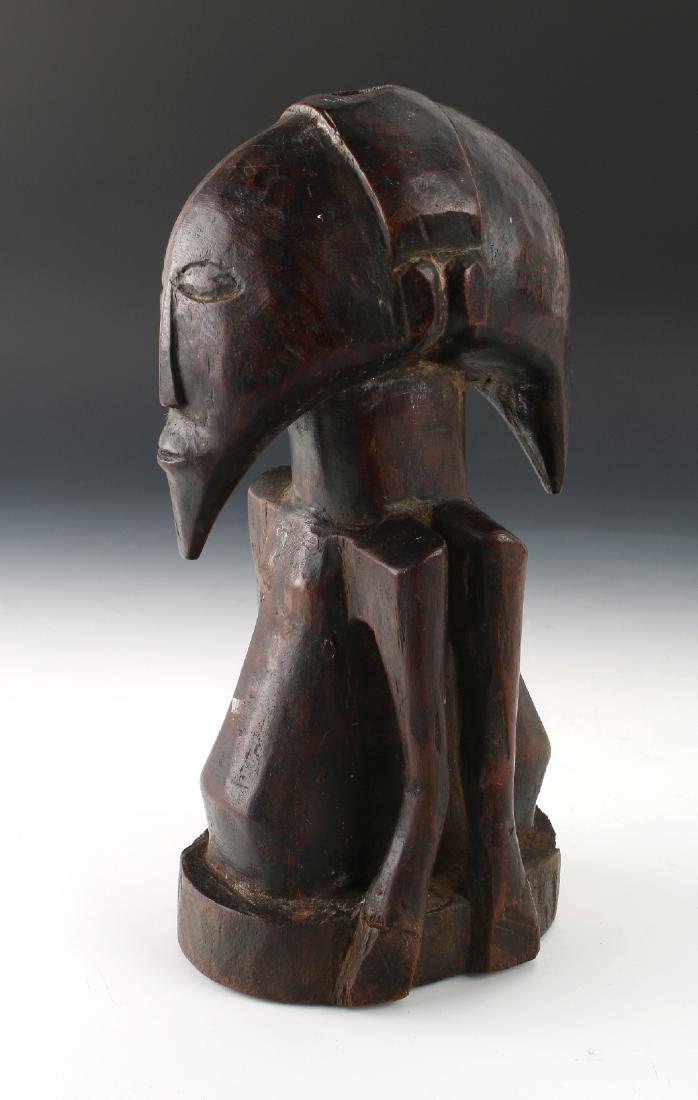 TWO SIDED AFRICAN STATUE: Two Sided African Statue: These back-to-back male figures are carved from hardwood. Seen from the side, the heads form a scythe shape. From the front, their chins come to a sharp point. Missi