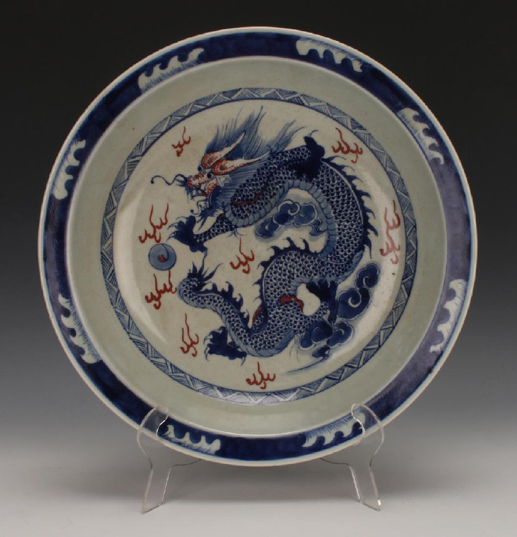 BLUE & WHITE KANGXI BOWL: Blue & White Kangxi Bowl: Blue and white with red accents, a dragon swirls in the center of this bowl. It's bordered with a diapered ring, the rim is in wave patterns. The outside has three brushs