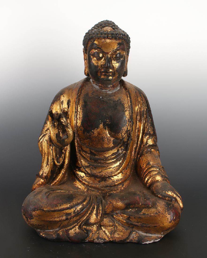 PAPIER MACHE BUDDHA WITH GOLD PAINT: Papier Mache Buddha With Gold Paint: A papier mache Buddha that is lacquered and gilded in gold paint. He is seated in the lotus position, one hand raised with thumb and middle finger touching.