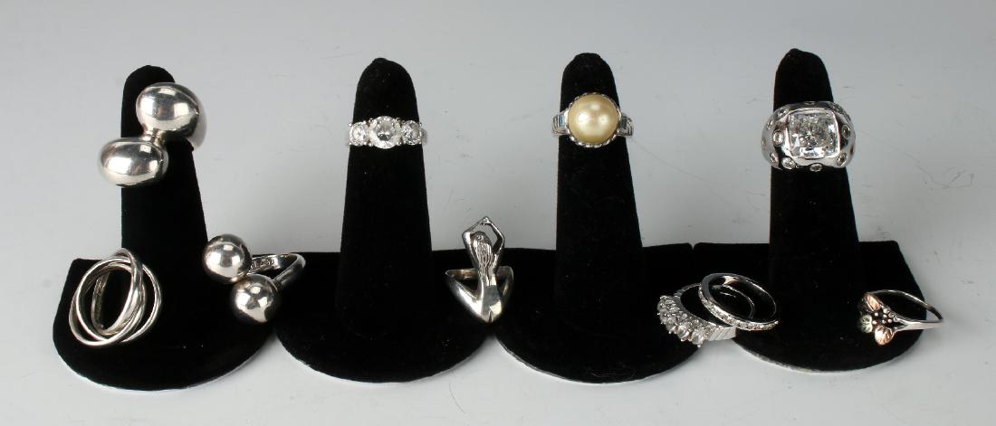 10 STERLING RINGS: 10 Sterling Rings: Some abstract shapes of sterling, some with faux diamonds, one representing a female nude. One large ring weighs 21.8g.