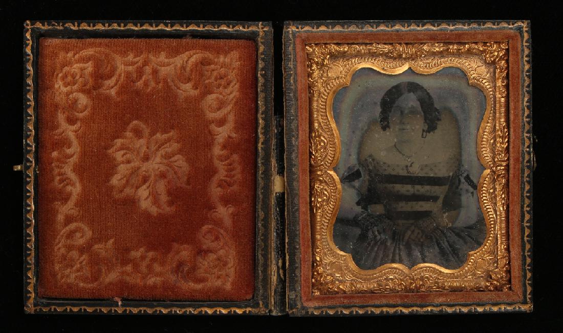 DAGUERREOTYPE OF A LADY IN CASE: Daguerreotype Of A Lady In Case: Daguerreotype on a 1/9 plate with a central over that appears to be amber stained. A formal portrait of a woman with center parted hair and lace fingerless gloves. She