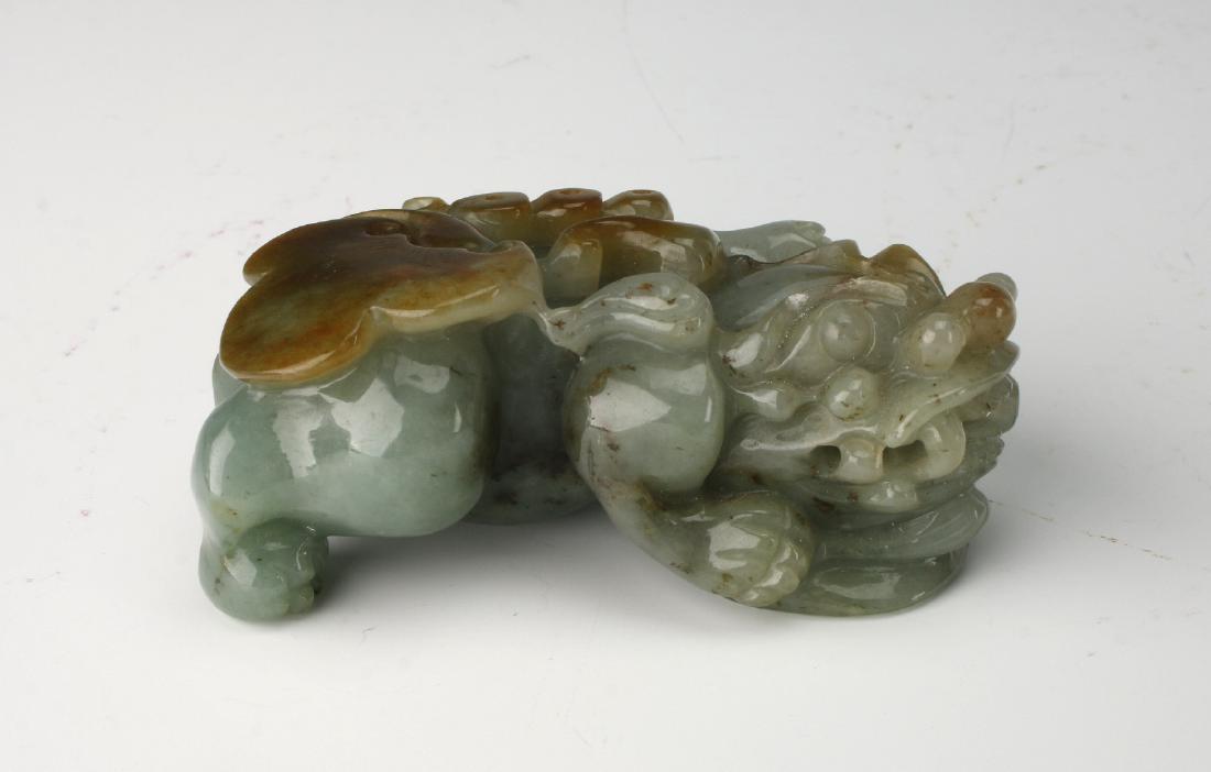 JADE FOO DOG CARVING: Jade Foo Dog Carving: The foo dog is bearing its teeth and has a ruyi carved on its back. Protecting a coin of good fortune, which is underneath him. 3 1/4" $2