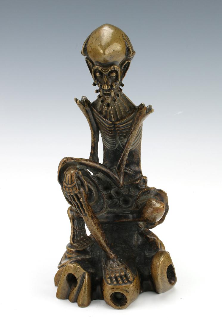 DHARMA DAMO FASTING GOD STATUE: Dharma Damo Fasting God Statue: A traditional representation of the skeleton thin Buddhist monk seated on a boulder. His hands are crossed over one knee. He is bearded and heavily browed. His bones an