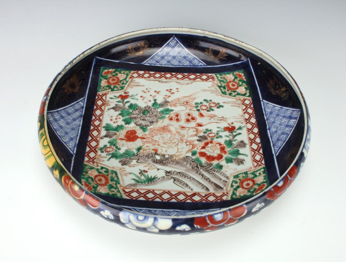 LARGE BOWL WITH FOO BEAST & FLOWERS: Large Bowl With Foo Beast & Flowers: A shallow bowl with a central square showing a red line drawing of a lion in a garden, offset by a diapered patterned square behind it. The outside is decorate