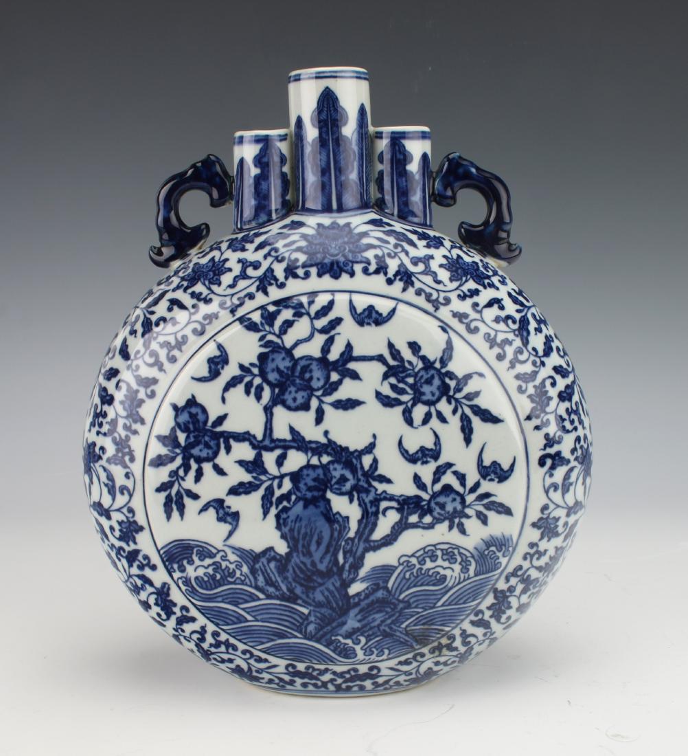 QIANLONG BLUE AND WHITE MOON FLASK: QIANLONG BLUE AND WHITE MOON FLASK: A blue and white moon flask decorated with peaches and bats on the body. The triple cylinder neck is flanked by pierced handles. All three necks have a plantain bor