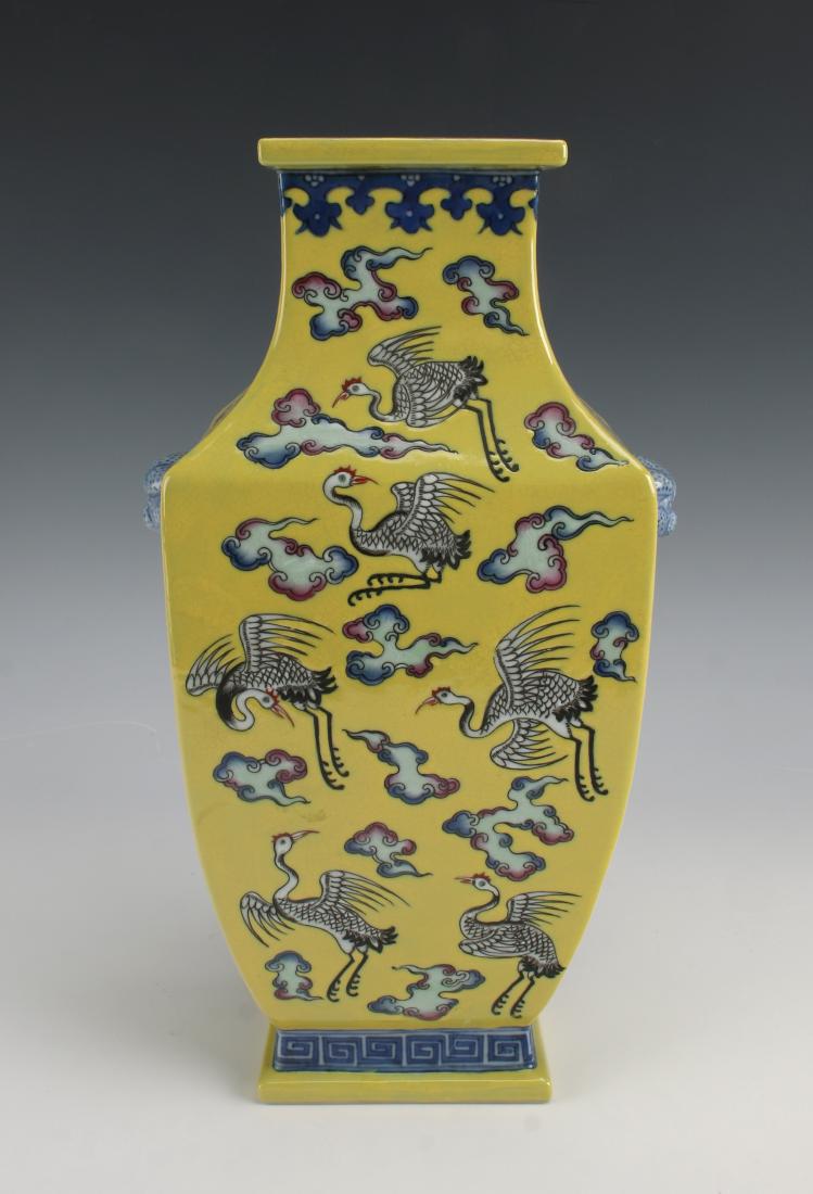YELLOW ENAMEL SQUARED CRANE VASE: YELLOW ENAMEL SQUARED CRANE VASE: Yellow background with a subtle craquelure finish decorated with flying cranes surrounded by multicolored clouds on the whole of the vase. Lion head handles with atta