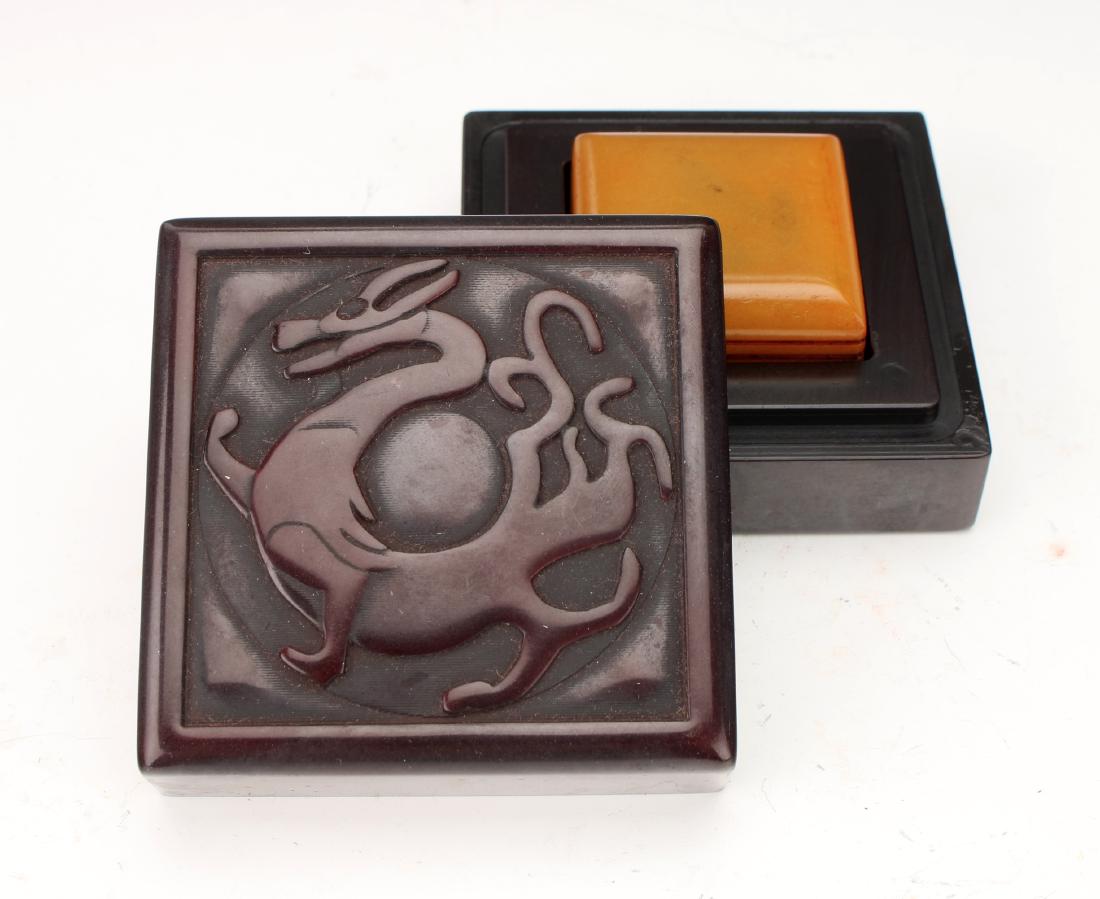 TIANHUANG SEAL IN DRAGON BOX: TIANHUANG SEAL IN DRAGON BOX: Square box with an incised dragon on the front and a meander border. Inside yellow stone seal. Marked on the bottom with incised characters. 2 3
