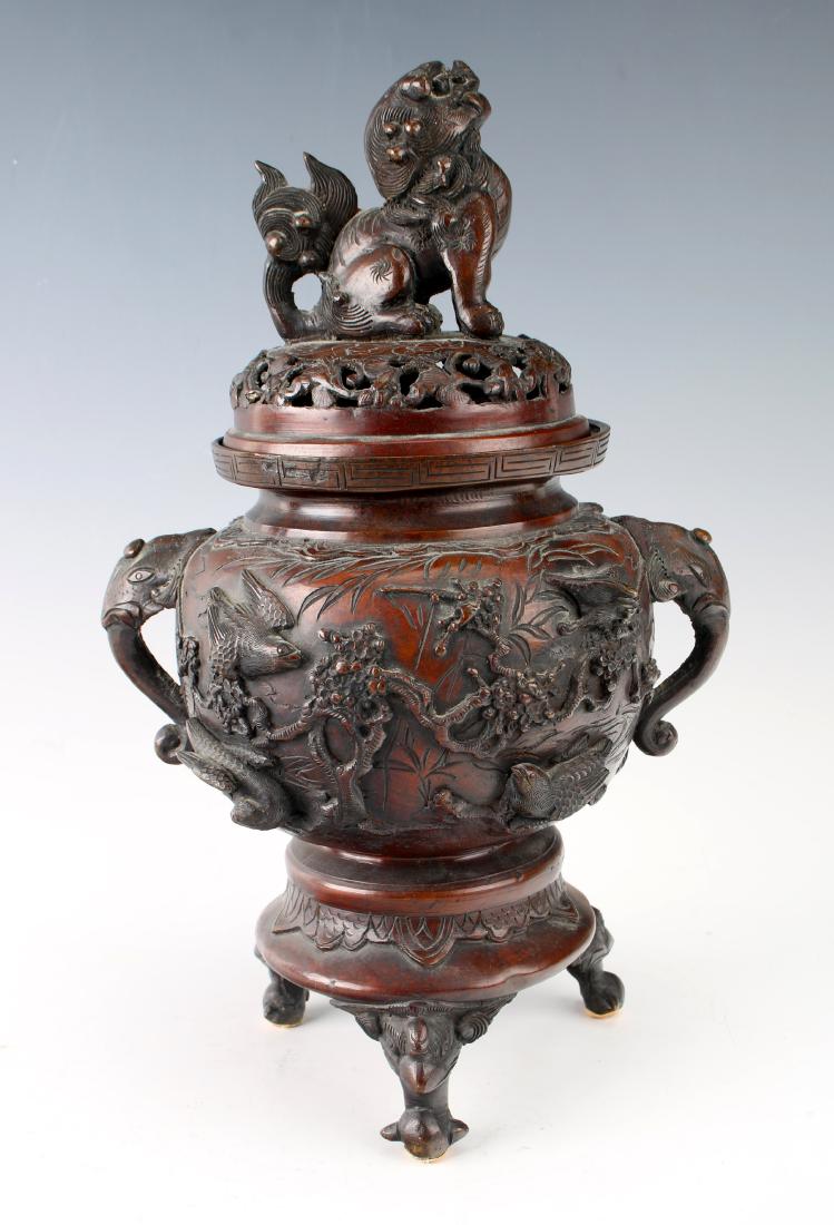 19TH C JAPANESE BRONZE CENSER: 19TH C JAPANESE BRONZE CENSER: A Japanese bronze censer on tripod feet with bird faces. The lid is topped by a large foo dog finial. The body has deep bas relief of birds and branches. Flanked by elep