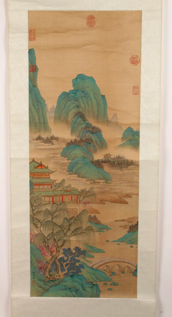 CHINESE VILLAGE LANDSCAPE WATERCOLOR SCROLL: CHINESE VILLAGE LANDSCAPE WATERCOLOR SCROLL: A village sits along a riverbank below misty mountain peaks in spring time. Trees, bridges, and boulders complete the scene. Calligraphy and artist marks o
