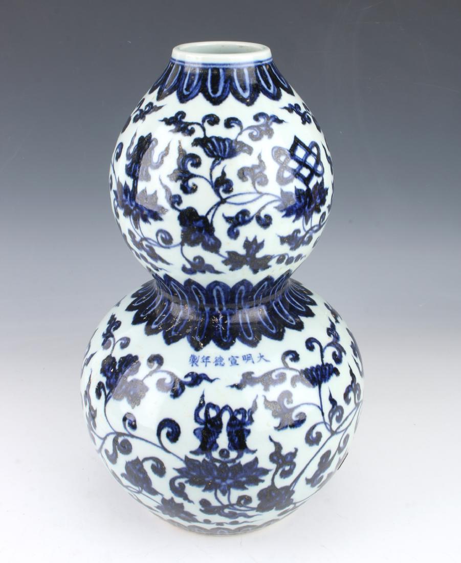 MING DYNASTY BLUE & WHITE DOUBLE GOURD VASE: MING DYNASTY BLUE & WHITE DOUBLE GOURD VASE: Flower and tendril designs over the body interrupted with plantain borders on the top, waist, and bottom. Marked with six characters on the front.