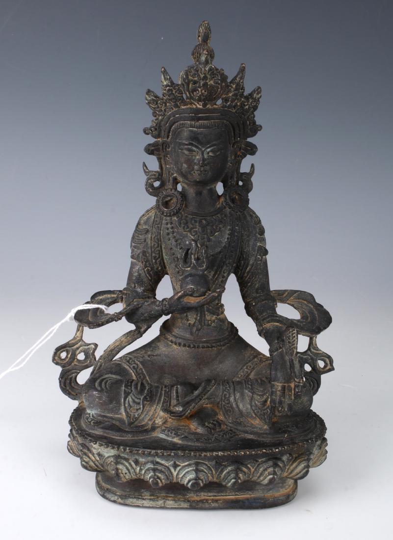 BUDDHA ON LOTUS PEDESTAL: BUDDHA ON LOTUS PEDESTAL: Buddha on lotus pedestal with dark verdigris patina. In one hand he is holding a flaming pearl and a feather in the other. He's wearing a headdress and many jewels.