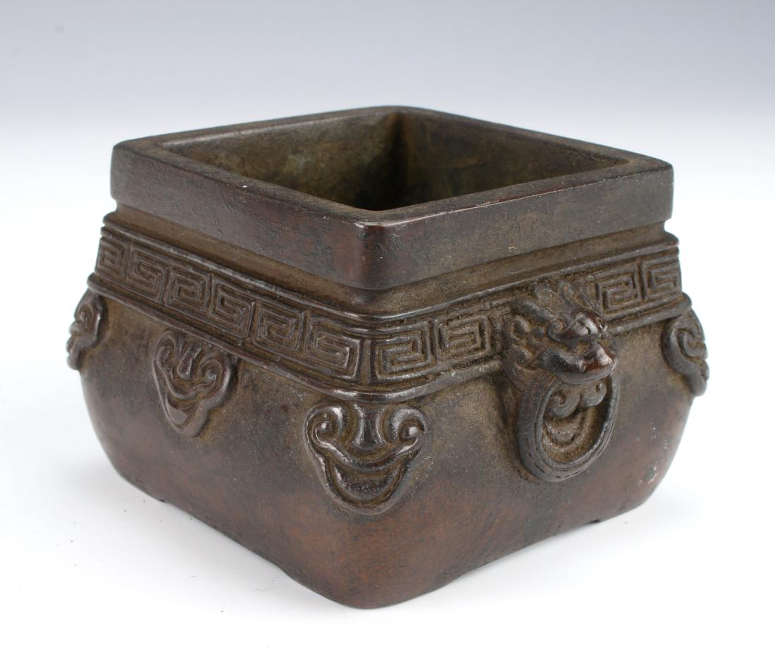 ANTIQUE CHINESE BRONZE CENSER: ANTIQUE CHINESE BRONZE CENSER: With a square rim and a rounded body. Has lion head handles with attached rings. A meander border over a ruyi border. Marked on the bottom. 3 1